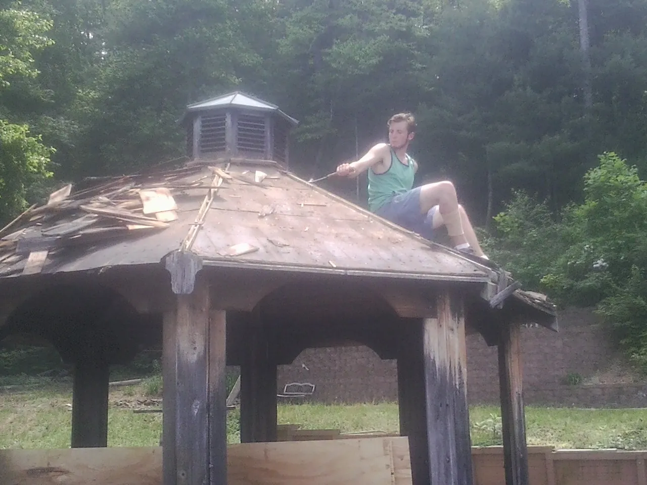Tearing the old roof off a wooden gazebo before new shakes in Kidder