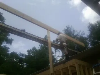 Carpenter setting a ridge beam over a new addition frame — Ice Dam Removal by Roofing Brothers in Kidder