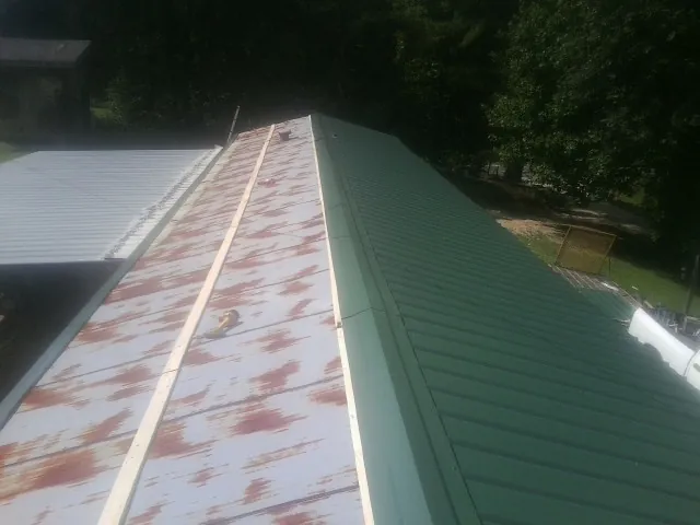 Old rusted panels beside newly installed green metal roofing — Wind Damage Roof Repair by Roofing Brothers in Kidder