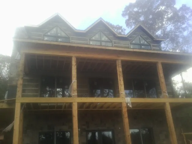 Dormers and porch framing on a large log home under construction — Roof Coating work by our crew in Kidder