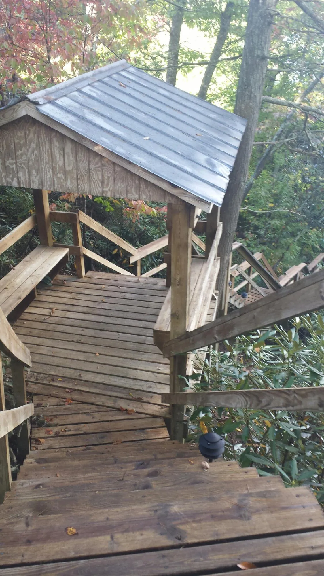 Metal roofed shelter over wooden steps on a wooded walkway — Skylight Repair & Installation work by our crew in Kidder