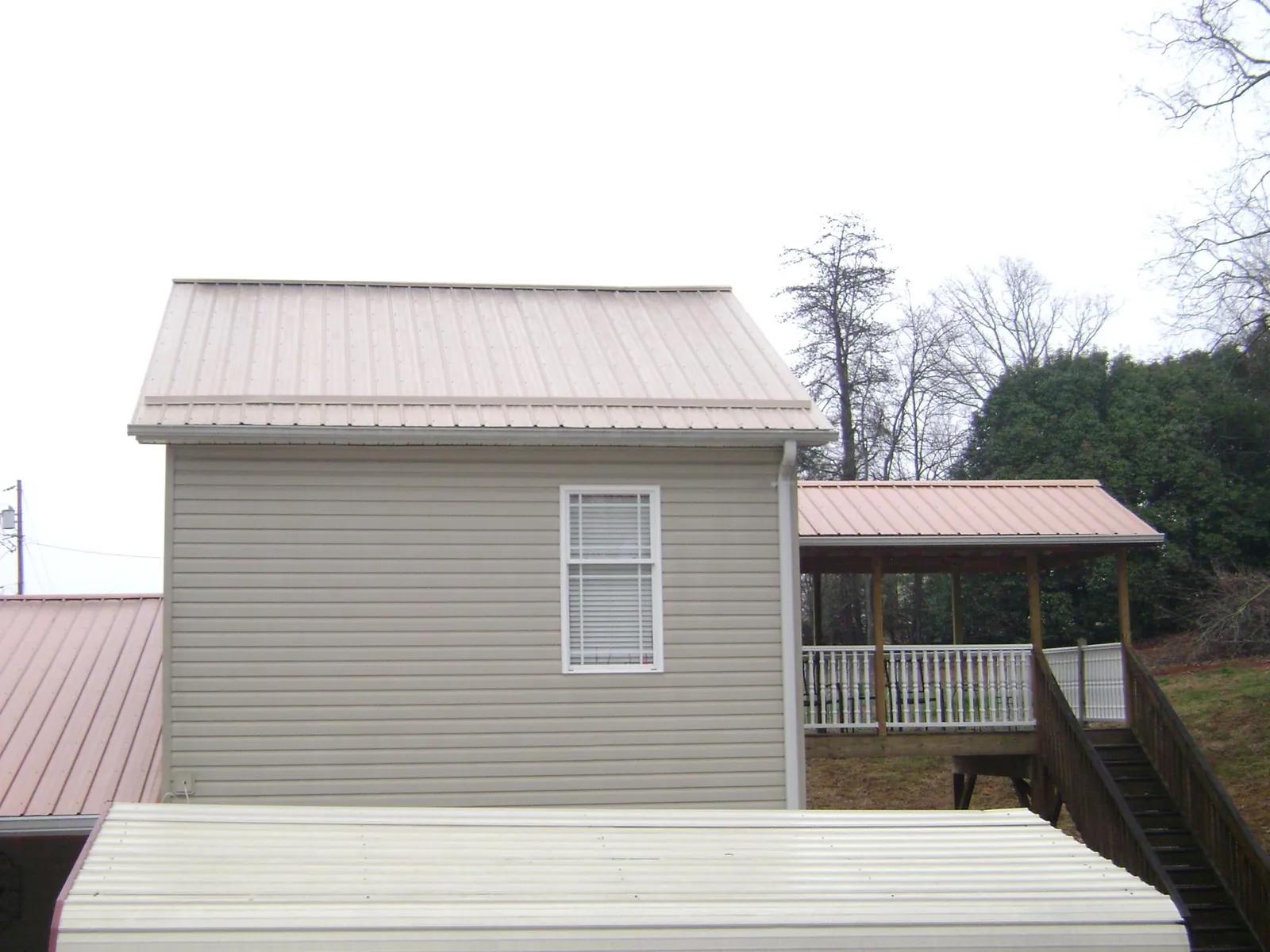 Tan metal roofs on a two story addition and attached porch, from a Roof Replacement job in Kidder