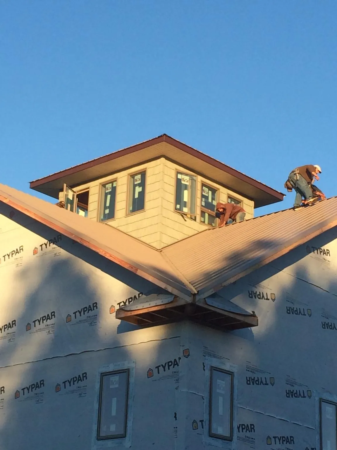 Roofers working around a rooftop cupola on a new metal roof at sunset — Roof Waterproofing in Kidder by Roofing Brothers